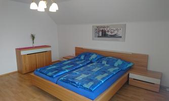 A cozy bedroom with a large double bed and colorful blankets. The furniture is made of wood and the room is bright and welcoming.