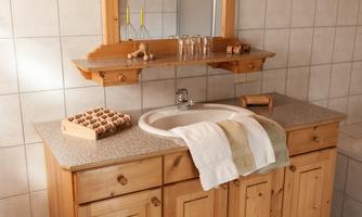 A cozy bathroom with a wooden washbasin and a round sink. Fresh towels and decorative elements give the space an inviting atmosphere.