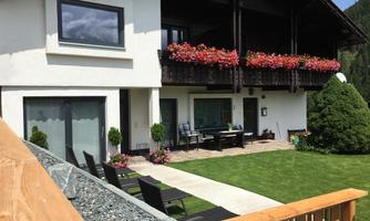 A cozy house with a balcony decorated with flowers. The garden is well-maintained and invites relaxation.