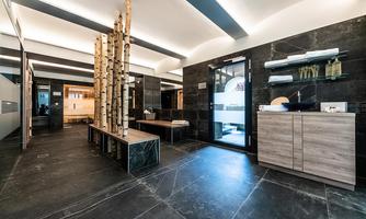 A modern interior design with smooth black tiles and wood accents. There are areas for relaxation and an elegant atmosphere.