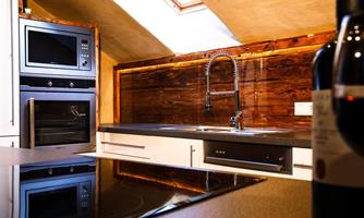 A modern kitchen with wooden paneling and large windows. The elegant appliances and the stylish faucet give the space a contemporary look.