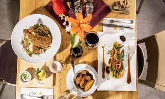 A beautifully set table with two artistically arranged dishes. There are also drinks and fresh flowers on the table.