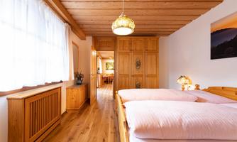 A cozy bedroom with wooden decor and two beds. Generous windows let in plenty of daylight.