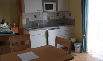 A small kitchen with a table and chairs. There are modern appliances and plenty of natural light.