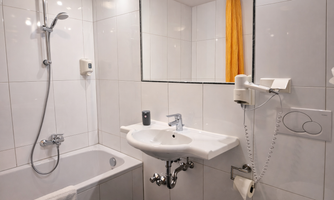 Bathroom with a bathtub, a sink, and a large mirror.