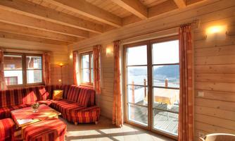 A cozy living space with wood-paneled walls and large windows. The red striped couch invites relaxation and offers a view outside.