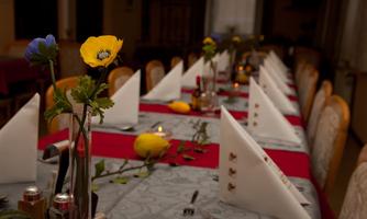 An elegantly set table with white napkins and colorful flowers. The table decoration also includes lemons and candles for a festive atmosphere.