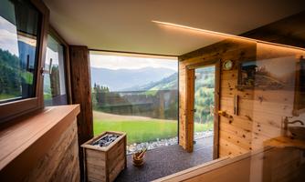 A modern interior with large windows and a view of the mountains. The room is made of wood and has a calm, relaxing atmosphere.