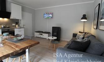 A modern apartment with a cozy living room and a fully equipped kitchen. The space is bright and inviting, ideal for relaxing stays.