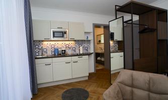 A modern kitchen with bright cabinets and an appealing tile pattern. In the background, an open living and bathroom area can be seen.