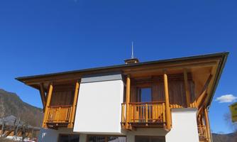 A modern building with wooden cladding and balconies. The clear blue sky forms a beautiful background.