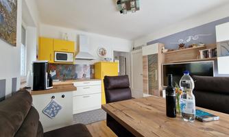 A modern kitchen with yellow cabinets and a cozy dining area. The wooden table and the brown chairs create an inviting atmosphere.