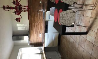 A modern kitchen with wood paneling and a dining area. The table has red place mats and matching chairs.