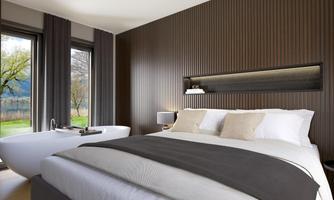 A modern bedroom with a large bed and an elegant bathtub. Large windows offer a view of nature.
