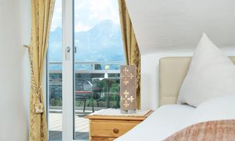 A cozy bedroom with a large window and a view of the mountains. The room is bright and welcoming, with carefully selected furnishings.