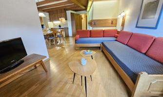 A modern living room with a red and blue sofa. The room has a wooden floor and a bright, inviting atmosphere.