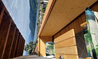 A cozy balcony with wooden paneling and a view of Lake Millstatt and the mountains.