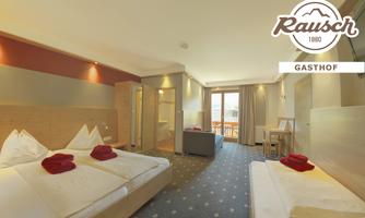 A modern room with two beds, decorated with red towels. The room has large windows and a cozy atmosphere.