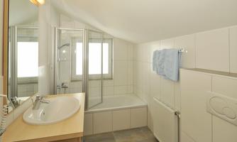 A modern bathroom with a shower and bathtub. Bright tiles and a sink create a friendly atmosphere.