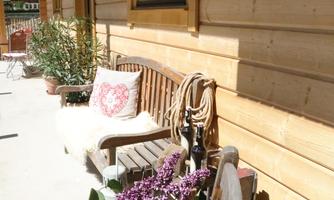 A cozy entrance with a wooden bench and colorful flowers. The warm wooden walls create an inviting atmosphere.