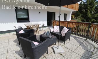 A cozy outdoor area with comfortable seating and a sun umbrella. The space invites relaxation and lingering.