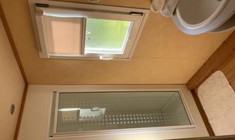 A modern bathroom with a shower cubicle and a sink. The light comes in through a window, creating a bright, friendly atmosphere.