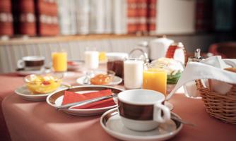 A hearty breakfast buffet with various drinks and foods. This includes fresh fruit, yogurt, jam, and pastries.