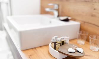 A modern bathroom with an elegant sink and wood paneling. Care products and glasses are placed on the table, creating an inviting impression.