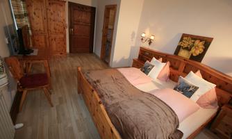 A cozy bedroom with a double bed and wooden furniture. The walls are light, and the room feels inviting.