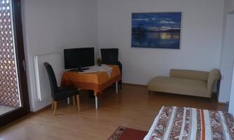 A bright living room with a sofa and a table. A TV stands on a table, and a picture hangs on the wall.