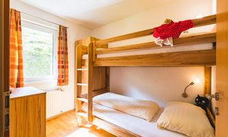 A simple children's room with a bunk bed and a window. The walls are bright and there are some colorful curtains.