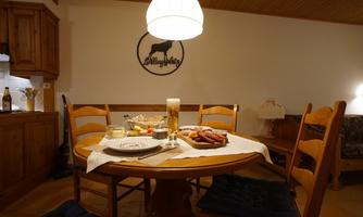 A laid table with a variety of food and drinks. In the background, there is a cozy wood paneling and a little lamp visible.