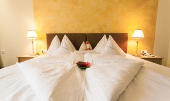 A cozy bedroom with a large bed and elegant bedding. The soft lighting creates a relaxed atmosphere.