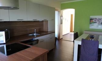 Modern kitchen with wooden worktops and an adjacent dining area. The walls are painted in a fresh green shade.