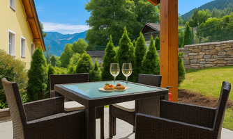 A cozy table with glasses and snacks on a terrace. In the background, green trees and mountains can be seen.
