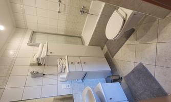 A modern bathroom with white tile design and bright walls. It features a bathtub, a sink, and various towels.