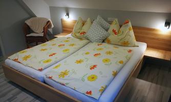 A cozy bedroom with a double bed and colorful flower bedding. There is also a comfortable seating area next to the bed.