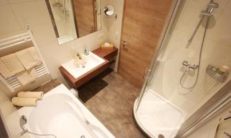 A modern bathroom with a shower cubicle and a bathtub. The decor is elegant and functional, with bright tiles and wooden accents.