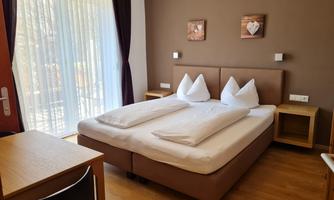 A cozy bedroom with a double bed and two pillows. The room has large windows and modern furniture.