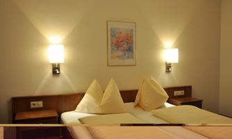 A cozy hotel room with two beds and yellow pillows. The room is brightly lit and features a piece of artwork on the wall.