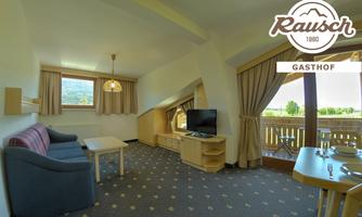A modern room in the Gasthof Rausch with a cozy seating area and a television. Large windows offer a view of the surrounding landscape.