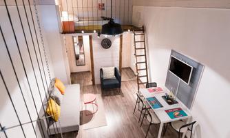 A modern, bright living room with a staircase leading to a sleeping area. There is a cozy sofa, a table, and a television on the wall.
