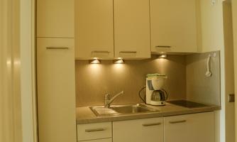 A modern kitchen with bright furniture and a practical sink. The lighting creates a pleasant atmosphere.