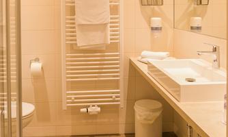 A modern bathroom with a shower and a bright sink. Towels are neatly placed on a towel rack.