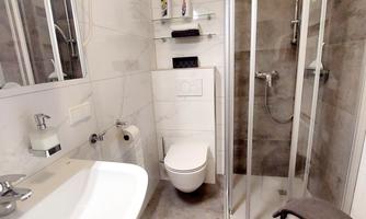 A modern bathroom with a shower, a sink, a toilet, and a mirror cabinet.