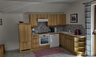 A modern kitchen with wooden cabinets and white appliances. The space is bright and inviting.