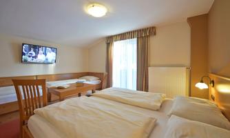 A cozy hotel room with a double bed and a single bed. The room has a television and plenty of daylight.