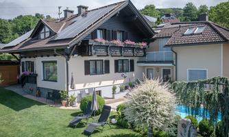 A beautiful house with a well-maintained garden and a terrace. In the background, you can see a pool and lounge chairs for relaxing.
