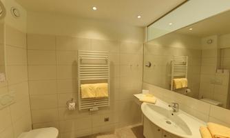 A modern bathroom with white tiles and bright towels. There is a towel rack, a sink, and a large mirror.