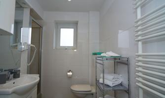 A modern bathroom with white tiles and bright walls. It features a sink, a shower, and a towel warmer.